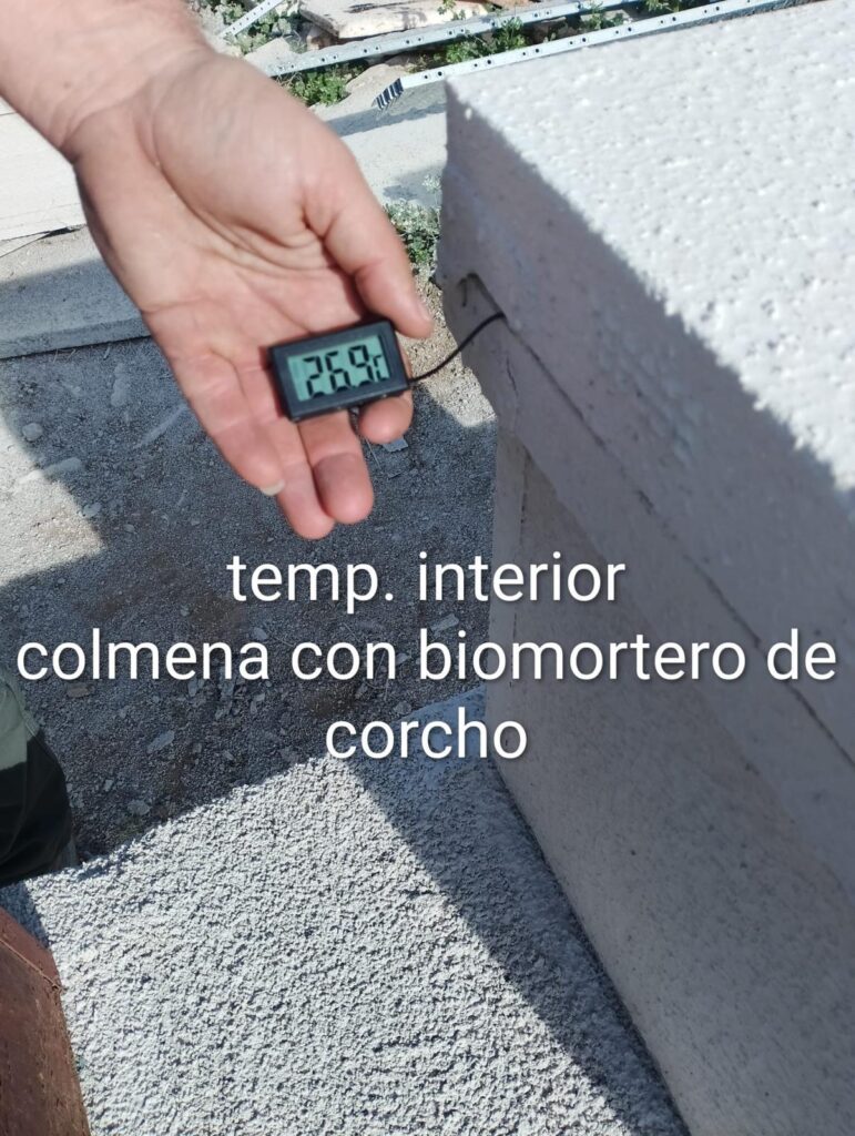 Termómetro digital que muestra una temperatura de 26.9 °C en el interior de una colmena aislada con biomortero de corcho, demostrando su eficiencia térmica.